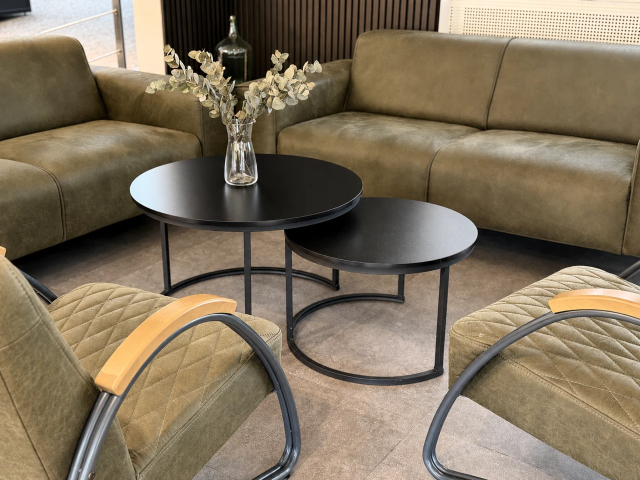 Sitzecke im Studio mit olivgrünen Sesseln und Sofa um zwei runde Beistelltische